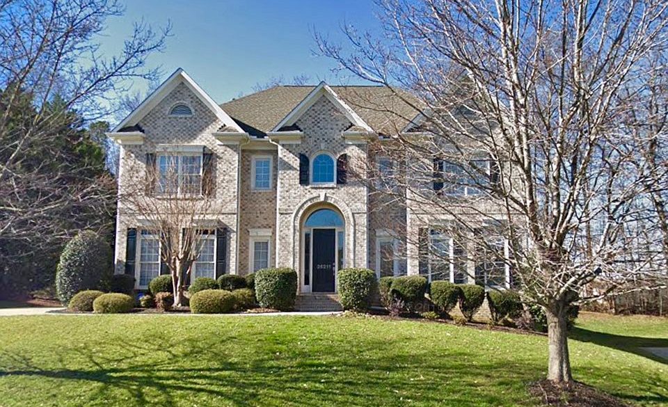 white brick colonial home in SC with green grass in front along with a couple trees